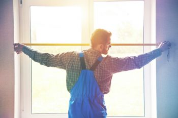 Service Man Installing Window With Measure Tape